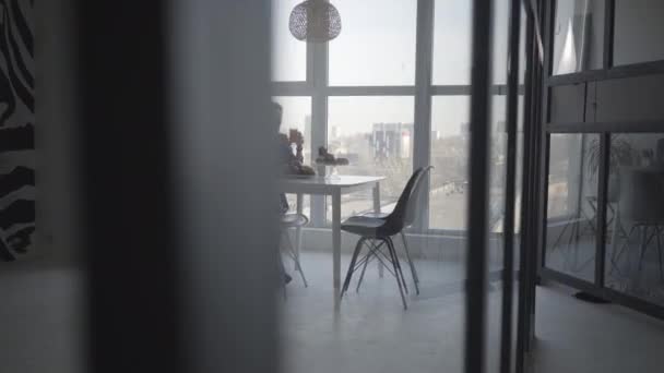 Wide shot of elegant adult Caucasian woman sitting at the table with orange juice and fruits. Confident businesswoman having breakfast in modern luxurious apartment. Lifestyle, success, richness. — Stock Video