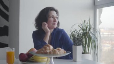 Sabahları gülümseyen ve esneme hareketleri yapan güzel beyaz bir kadın. Pencereden dışarı bakan kendinden emin mutlu iş kadınının portresi. Mutluluk, yaşam tarzı, neşe, zenginlik.