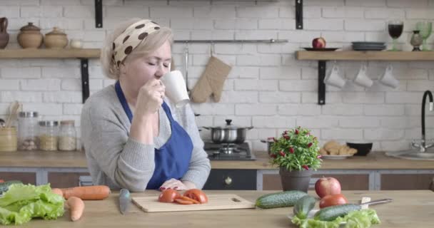 コーヒーや紅茶を屋内で飲む悲しい成熟した白人女性。朝食を作る前に台所で休んでいるシニア主婦。家事、料理、ライフスタイル。シネマ4k｜ProRes HQ. — ストック動画