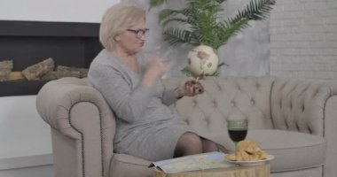 Neşeli zengin Kafkasyalı emekli dünyayı döndürüyor ve gülüyor. Gözlüklerini çıkarıp gülümseyen varlıklı yaşlı kadın. Turizm, yaşam tarzı, zenginlik, seyahat. Sinema 4k ProRes Merkezi.