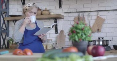 Sabahları kahve içip yemek tarifleri okuyan olgun sarışın bir kadının portresi. Ciddi bir orta yaşlı emeklinin kahvaltı hazırlamaya karar vermesi. Yaşam tarzı, aşçılık. Sinema 4k ProRes Merkezi.