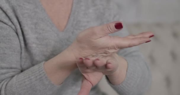 Primo piano di mani caucasiche più anziane femminili che applicano la crema idratante. Donna di mezza età irriconoscibile che si prende cura della sua pelle. Bellezza, invecchiamento, stile di vita. Cinema 4k ProRes HQ . — Video Stock