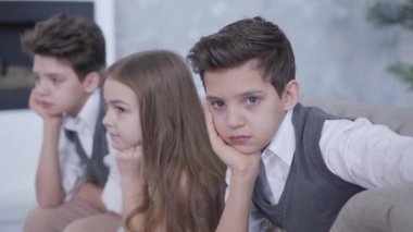 Kameraya, kendisine ve ikiz kardeşine sarılmış neşeli kız kardeşi olarak bakan düşünceli beyaz çocuğun portresi. Dost canlısı kardeşler evde birlikte vakit geçiriyorlar. Yaşam tarzı, birlik, rahatlık..