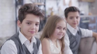 Yakışıklı beyaz bir çocuktan, onun ve ikiz kardeşinin kafalarına boynuz takan neşeli küçük kız kardeşine odaklan. Erkekler kıza dönüyor, çocuklar utangaç bir şekilde gülümsüyor..