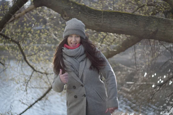 Iloinen ruskeaverikkö harmaasilmäinen tyttö näyttää peukaloa ulkona. Muotokuva iloinen söpö valkoihoinen nainen hauskaa puistossa aurinkoisena syyspäivänä. Vapaa-aika, elämäntapa, onnellisuus, ilo . — kuvapankkivalokuva