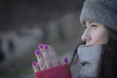 Açık havada dua eden genç bir kadının yan görüntüsü. Sevimli esmer kız el ele tutuşarak bakışlarını kaçırıyor. Yaşam tarzı, inanç, boş zaman.
