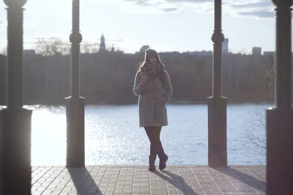 Muotokuva huomaavainen nuori nainen kahvikuppi seisoo puistossa taustalla järven. Aikuinen brunette tyttö katselee pois ja ajattelee. Elämäntapa, vapaa-aika, rentoutuminen . — kuvapankkivalokuva