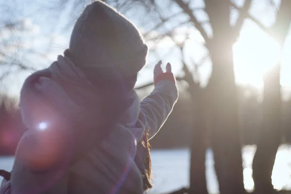 Ugjenkjennelige brunette-jenter som fanger solstråler med hånden. Ung, kaukasisk kvinne med strukket hånd som står utendørs på en innsjø eller elvebredd . – stockfoto