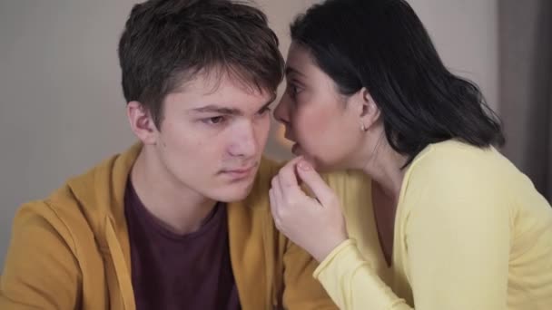 Close-up of brunette Caucasian woman whispering on ear of teenage boy. Mother sharing secrets with teen son. Trust, unity, reliance, lifestyle. — Stock Video