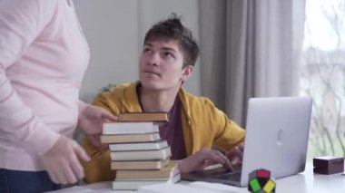 Genç beyaz tenli esmer çocuk dizüstü bilgisayarda oynarken annesi bir yığın kitapla çıkageldi. Kadın edebiyatı masaya yatırıyor, oyuncu ailesiyle tartışıyor. Çatışma, eğitim, yaşam tarzı.