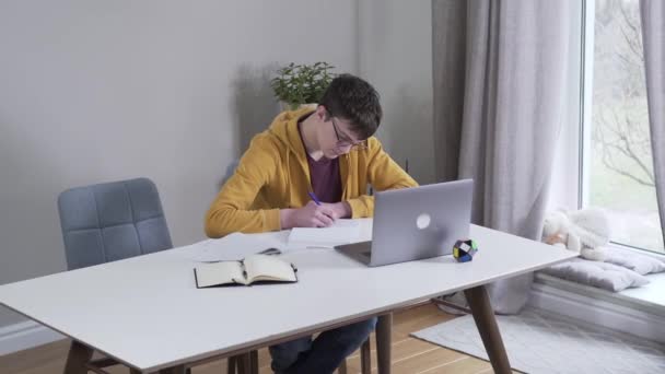 Vista superior de adolescente caucásico morena chico haciendo la tarea. Guapo estudiante universitario inteligente estudiando duro en el interior. Estilo de vida, educación, atención plena . — Vídeo de stock