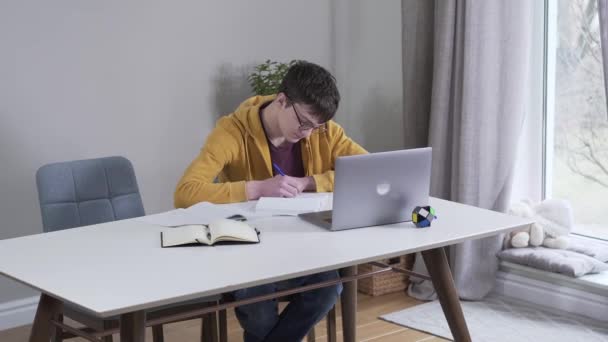 Mujer morena caucásica adulta trayendo un montón de libros a un estudiante adolescente cansado que trabaja en la mesa. Niño con gafas que estudia mucho en casa. Madre sobrecargando a estudiante. Educación, inteligencia — Vídeo de stock