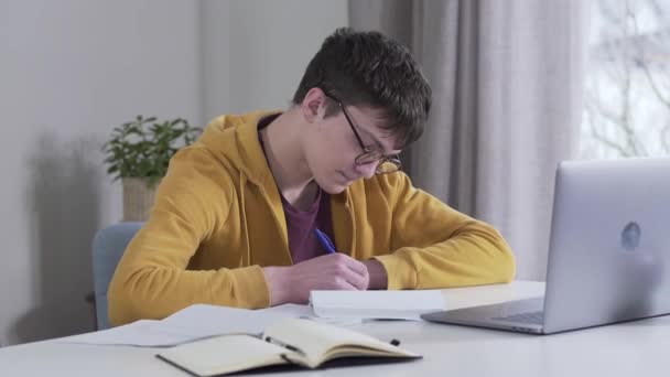 Portret van een slimme blanke jongen in een bril kijkend naar een stapel boeken gebracht door moeder en zangeres. Moe student werkt onder strikte controle van de ouder. Briljant, intelligentie, onderwijs. — Stockvideo