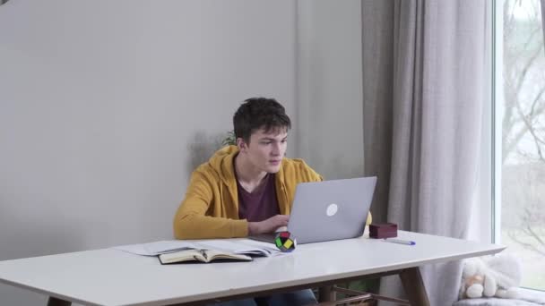 Portrait of absorbed Caucasian boy gaming as mother putting stack of book on table angrily and slapping back of his head. Dissatisfied woman forcing son to study. Distracting, education, social media. — Stock Video