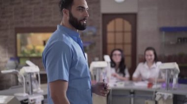 Orta Doğulu stomatoloji öğretmeninden, soru soran beyaz kız öğrenciye odaklanma değişiklikleri. Profesyonel dişçi, dişçi kliniğindeki asistanlara ders veriyor. Eğitim.