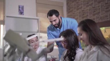 Pozitif Orta Doğulu profesyonel stomatolog diş sağlığı kliniğinde öğrencilere ders veriyor. Genç yakışıklı adam seyircilere diş yapısını anlatıyor. Meslek, dişçilik, eğitim.