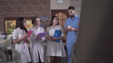 Orta Doğu profesöründen sonra not yazan beyaz dişçi öğrencilerinin portresi. Kendine güvenen adam stomatolog asistanlara ders veriyor. Meslek, eğitim, tıp.