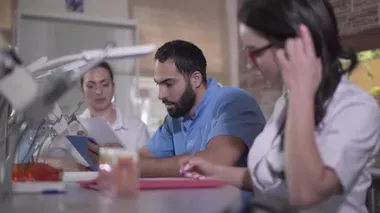 Çok ırklı grup arkadaşları dişçilik okuyor. Beyaz kadın ve Orta Doğulu adamın dişleri dökülmüş ve notlarla masada oturuşunun yan görüntüsü. Tıp, meslek, eğitim.