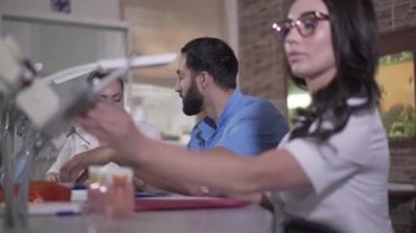 Orta Doğulu ve Kafkas diş hekimliği öğrencileri arka planda önde enstrüman kullanan esmer kadın olarak konuşuyorlar. Ciddi grup arkadaşları stomatolojiyi tartışıyor. Öğrenme, öğrenme, tıp.