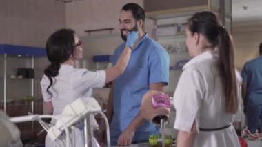 Genç esmer, beyaz kadın diş implantlarını erkek Orta Doğulu meslektaşlarıyla karşılaştırıyor. Kendine güvenen öğrenciler stomatoloji okuyor. Yaşam tarzı, tıp, meslek, dişçilik.