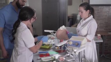 Genç dişçi asistanları mankenlere diş implantı takıyor. Beyaz kadınlar ve orta doğulu erkek stomatoloji manipülasyonu yapıyor. Yaşam tarzı, ilaç, sağlık hizmetleri.