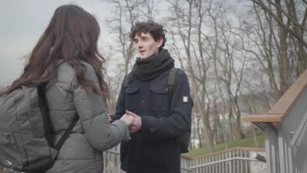 Portret van een jonge, liefdevolle blanke jongen die hand in hand met een brunette praat. Een gelukkige man met krullend haar en een vriendin in het herfstpark. Romantiek, saamhorigheid, verbinden, liefde. — Stockvideo