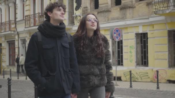 Portrait of happy young Caucasian couple walking on city street and chatting. Positive boy and girl travelling. Urban lifestyle, tourism, lifestyle, leisure. — Stock Video