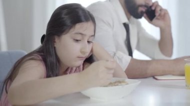Üzgün Orta Doğulu güzel bir kızın portresi, sabah kahvaltısında telefonda konuşan tanınmayan bir babaya bakıyor. Üzgün şirin kız iç çekiyor. Çocukluk, ihmal, iş..