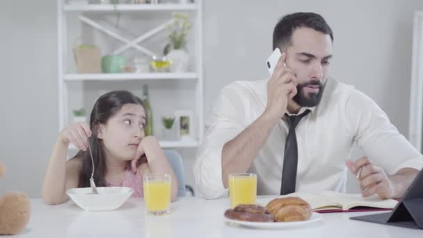 Közel-keleti kislány nézi, ahogy apa reggel telefonál. Reggeli elfoglalt ember és unatkozó lánya otthon. Életmód, üzlet és család, elhagyás. — Stock videók