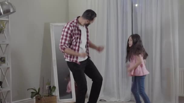 Positivo pai e filha do Oriente Médio dançando em casa. Jovem homem alegre e menina bonita se divertindo dentro de casa nos fins de semana. Estilo de vida, paternidade, infância, felicidade . — Vídeo de Stock