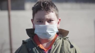 Kahverengi gözlü, koruyucu maskesini çıkarıp kameraya gülümseyen Kafkas esmer çocuğun yakın plan portresi. Coronavirus 'un sonu karantina, ilaç, Covid-19.