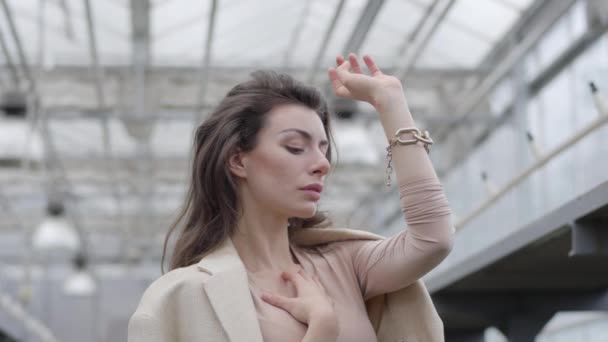 Retrato de enigmática mujer morena con ojos marrones sosteniendo la mano y pensando. Hermosa dama pensativa en traje elegante. Cámara moviéndose hacia arriba . — Vídeos de Stock