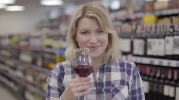 Retrato de joven sommelier femenino profesional oliendo vino tinto y estirando el vidrio a la cámara. El enfoque cambia de cara a beber en la copa de vino. Profesión, estilo de vida, industria del alcohol . — Vídeo de stock