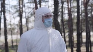 Şehir parkında yürüyen, güvenlik kıyafetli, ciddi bir beyaz adam. Dışarıda koruyucu eldiven ve maske takan yakışıklı bir çocuk. Coronavirus karantinası, WHO tavsiyeleri, salgın tehlikesi.
