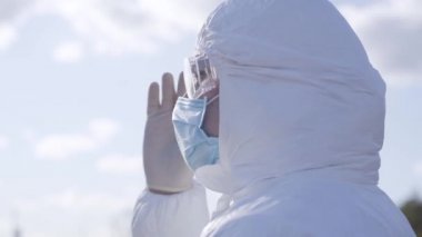 Yüz maskeli üzgün beyaz adamın koruyucu gözlüklerini çıkartırken yakın plan görüntüsü. Koronavirüs karantinası sırasında güneşli bir bahar gününde dışarıda duran genç adamın portresi. Covid-19, salgın hastalık.