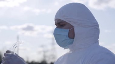 Koruyucu gözlük takan ciddi bir delikanlının yakın çekimi. Beyaz takım elbiseli ve maske takan kendine güvenen beyaz adam bahar gününü banliyöde geçiriyor. Coronavirus salgını, Covid-19 karantina.