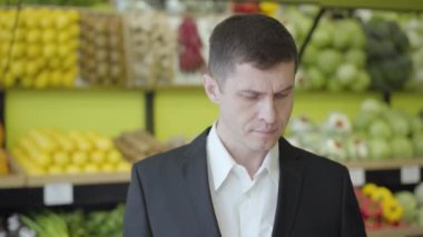 Markette armut seçen ciddi bir beyaz adamın yakın plan portresi. Yüzünde tatminkar bir ifadeyle sarı meyve kokan yakışıklı bir adam. Vejetaryenlik, yaşam tarzı, sağlıklı beslenme..