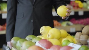 Marketten sarı armut seçen tanınmamış beyaz bir adam. Erkek vejetaryen perakende dükkanından meyve seçiyor. Yaşam tarzı, sağlıklı beslenme, vitamin yiyeceği..