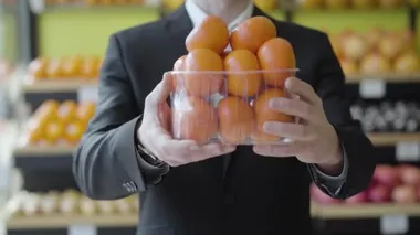 Tanımlanamayan beyaz adam kameraya lezzetli mandalina sepeti uzatıyor. Erkek eller markette lezzetli portakal meyvelerini tutuyor. Sağlıklı beslenme, vitamin yiyeceği, diyet, yaşam tarzı.