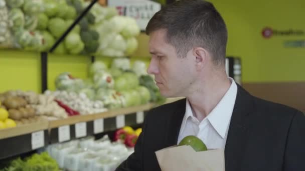 Close-up de homem caucasiano adulto confiante escolhendo pomelo no supermercado, colocando frutas cítricas em pacote e partida. Bonito morena cara comprando comida vegan saudável na loja de varejo. Estilo de vida . — Vídeo de Stock