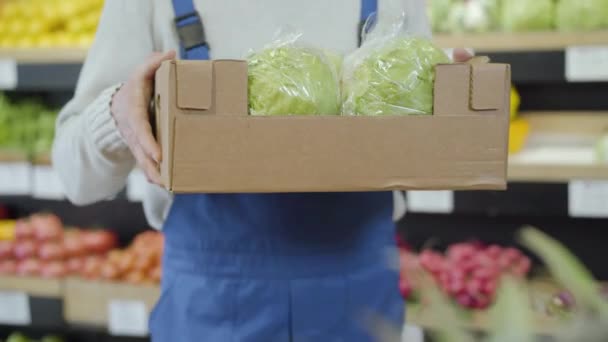 Manliga kaukasiska händer sträcker låda med färska kål till kameran. Oigenkännlig manlig anställd som visar vegetarisk hälsosam mat i mataffären. Handel, detaljhandel, affärer, vegetarianism. — Stockvideo