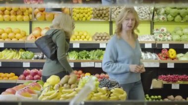 Markette sıra sıra yürüyen ve konuşan iki son sınıf beyaz kadının portresi. Yetişkin ev hanımları perakende dükkanında alışverişleri tartışıyor. Tüketim, yaşam tarzı, alışveriş, yemek pişirme.