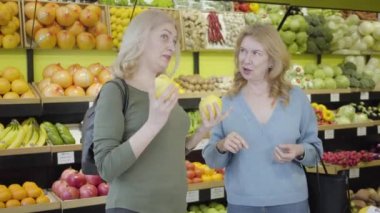 Markette duygusal olarak konuşan ve el kol hareketi yapan olgun beyaz kadınlar. Süpermarkette dedikodu yapan pozitif ev kadınları yemek pişirmek için sağlıklı yiyecekler satın alıyorlar. Yaşam tarzı, neşe, tüketim.