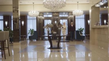 Kafkas erkek ve kadının seyahat çantasıyla lüks otel girişine girerken ve resepsiyona yaklaşırken son derece geniş bir açı. Zengin çift birinci sınıf konaklama yerlerinde kalıyor. Turizm, lüks