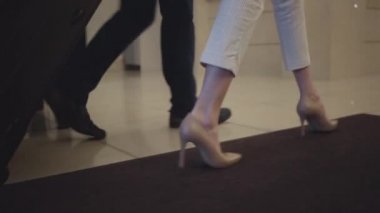Otel resepsiyonuna doğru yürüyen erkek ve beyaz kadın ayaklarını takip eden kamera. Zengin müşteriler giriş yapıyor. Bavulları lüks konaklarda olan zengin bir adam ve kadın. Turizm, seyahat, yaşam tarzı.