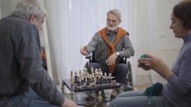 Yanında örgü ören yaşlı bir kadın olarak huzurevinde satranç oynayan, gözlüklü, kendine güvenen yaşlı bir adam. Pozitif Kafkas emeklileri evde sakin bir akşam geçiriyorlar..