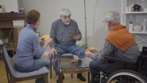 Πορτρέτο του πρεσβύτερου Καυκάσου που παίζει χαρτιά με φίλους στο γηροκομείο. Συνταξιούχοι απολαμβάνουν το βράδυ σε εσωτερικούς χώρους. Εστίαση αλλαγών από φόντο σε μέτωπο. — Αρχείο Βίντεο