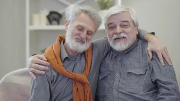 Retrato de dois homens caucasianos de cabelos grisalhos falando à câmera e mostrando os polegares para cima. idosos felizes aposentados posando em casa de repouso . — Vídeo de Stock
