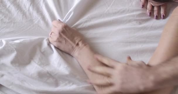 女性の手のひらを絞るベッドシーツを取る男性白人シニア手のトップビュー。愛の認識できない成熟したカップルは、午前中に寝室でセックスをしている。愛、楽しみ。シネマ4k｜ProRes HQ. — ストック動画