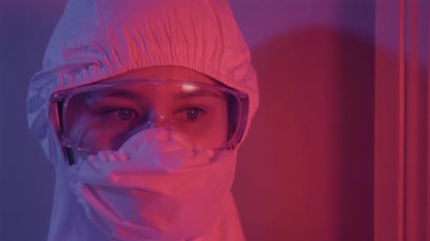 Primer plano de la cara femenina en traje antiviral y gafas protectoras. Mujer caucásica joven que trabaja en la industria de la salud durante la pandemia de coronavirus. Medicina, Covid-19, peligro global . — Vídeo de stock